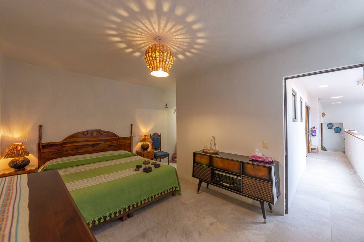 Un dormitorio con una cama, lámparas de noche, un aparador y una lámpara en el techo.