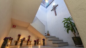 A staircase with a cross on the wall, potted plants, and candles on the steps. - La Casa Carlota (Oaxaca)