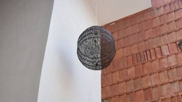 Una habitación con una máquina de coser, un cactus y una lámpara colgante.