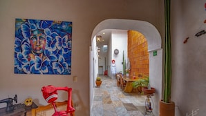 A hallway with a large painting, a skeleton, and a cactus. - La Casa Carlota (Oaxaca)