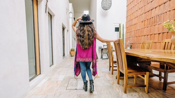 A person walking through a corridor with a dining area on the right. - La Casa Carlota (Oaxaca)