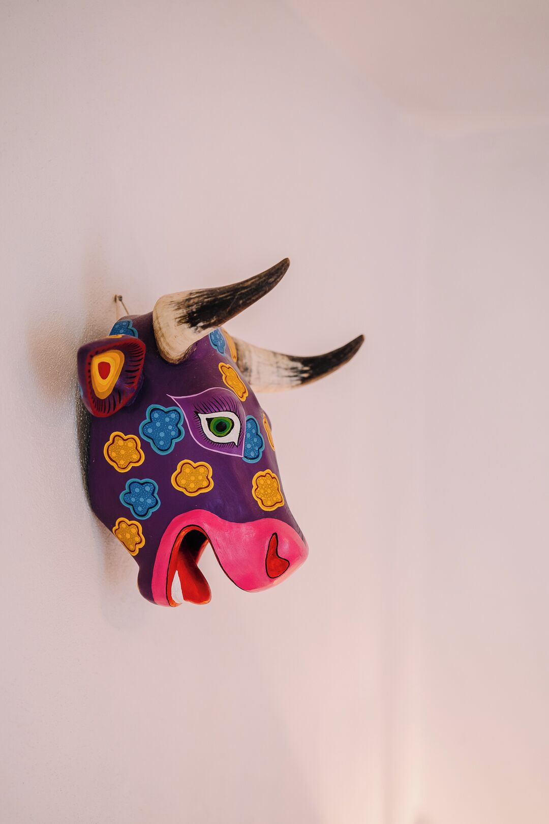 Escultura colorida de cabeça de touro com chifres e um olho pintado.