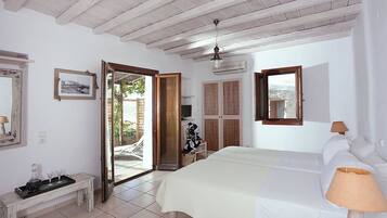 Quarto com cama, luminária de cabeceira, mesinha com bandeja, espelho e porta para área externa.
