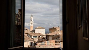 Blick durch ein Fenster auf eine Stadt mit einem markanten Turm und traditioneller Bebauung.