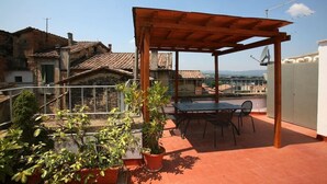 Eine Dachterrasse mit Holz-Pergola, Kübelpflanzen und einem Tisch mit Stühlen.