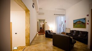 Ein Wohnzimmer mit Sofa, Couchtisch und Lampe. An der Wand hängt ein Bild und ein Fenster mit Vorhängen.