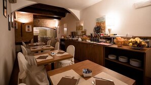 Ein Restaurant mit Holztischen und -stühlen, einem Küchenbereich und einer Buffettheke mit Früchten und Speisen.