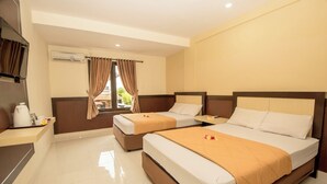 A hotel room with two beds, a small table, a TV, and an air conditioning unit. - Puri Nusa Indah (Denpasar)