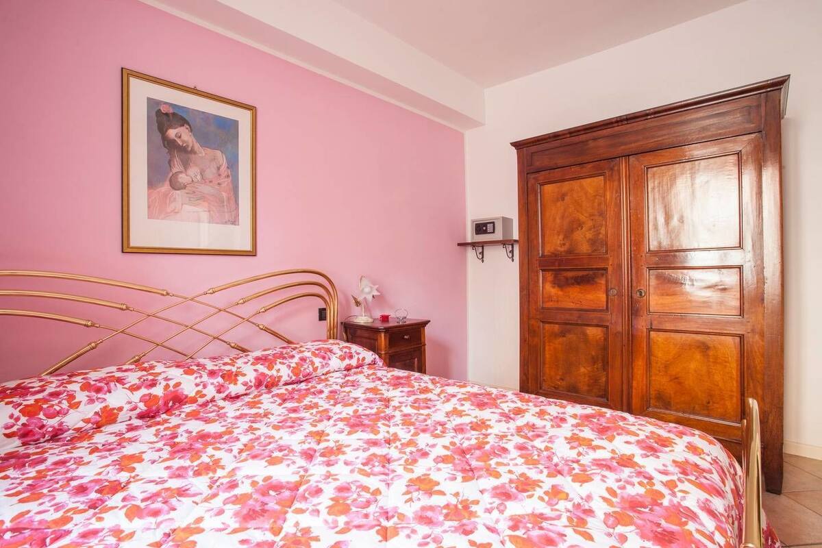 Une chambre à coucher avec un lit, une armoire en bois, une table de chevet et un tableau encadré au mur.