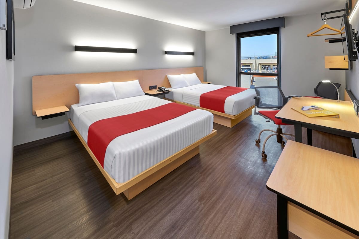 A hotel room with two beds, a desk, and a chair.