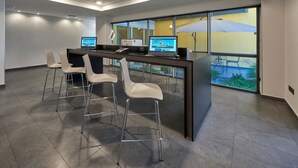 A modern office space with a reception desk, two computer monitors, and four white chairs. - City Express by Marriott Tijuana Otay (Tijuana)