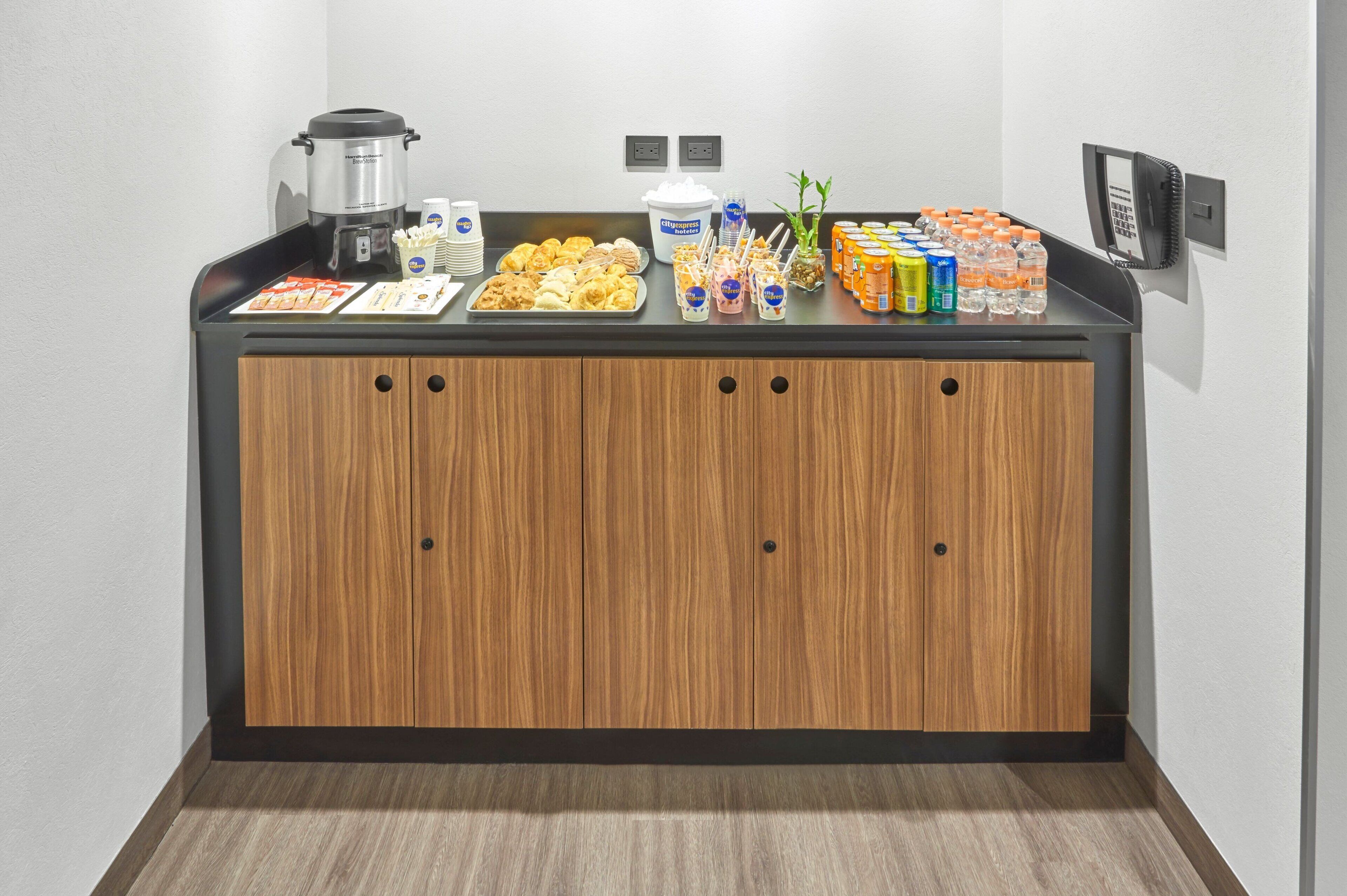 A buffet counter with a coffee maker, a bowl of ice cream, and various snacks.