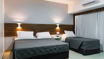 Una habitación de hotel con cama, mesitas de noche y un equipo de aire acondicionado.