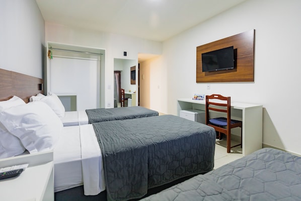 Habitación de hotel con dos camas, un escritorio, una silla y un televisor montado en la pared.