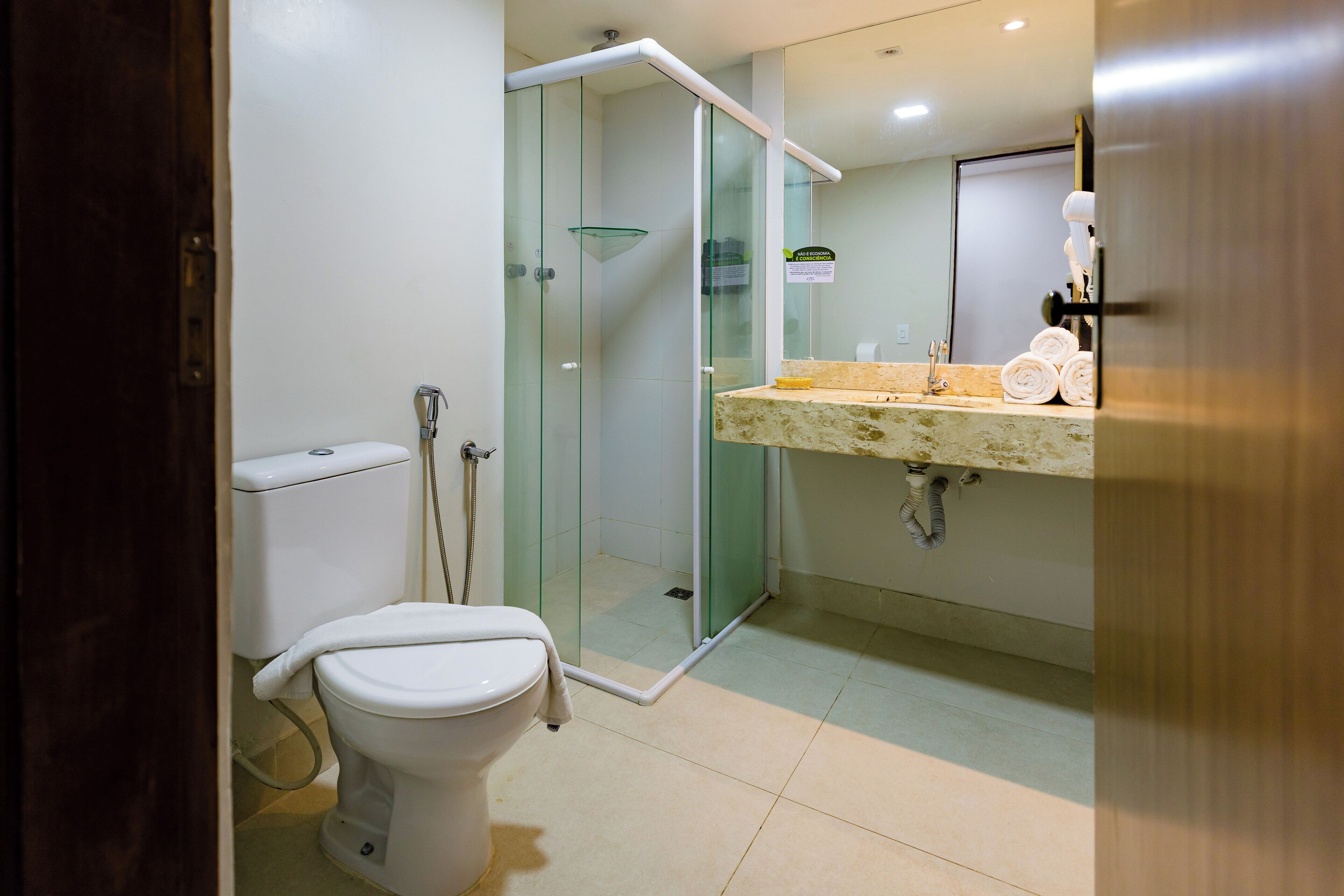 A modern bathroom with a glass-enclosed shower, a toilet, and a vanity with a towel rack.