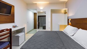 Una habitación de hotel con una cama, un escritorio, un televisor y un refrigerador.