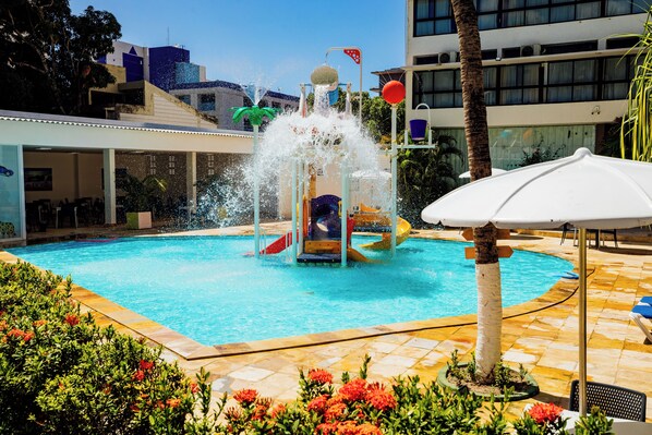 A swimming pool with a water play area, surrounded by a tiled deck and potted plants. - EL ARAM BEACH & CONVENTION (João Pessoa)