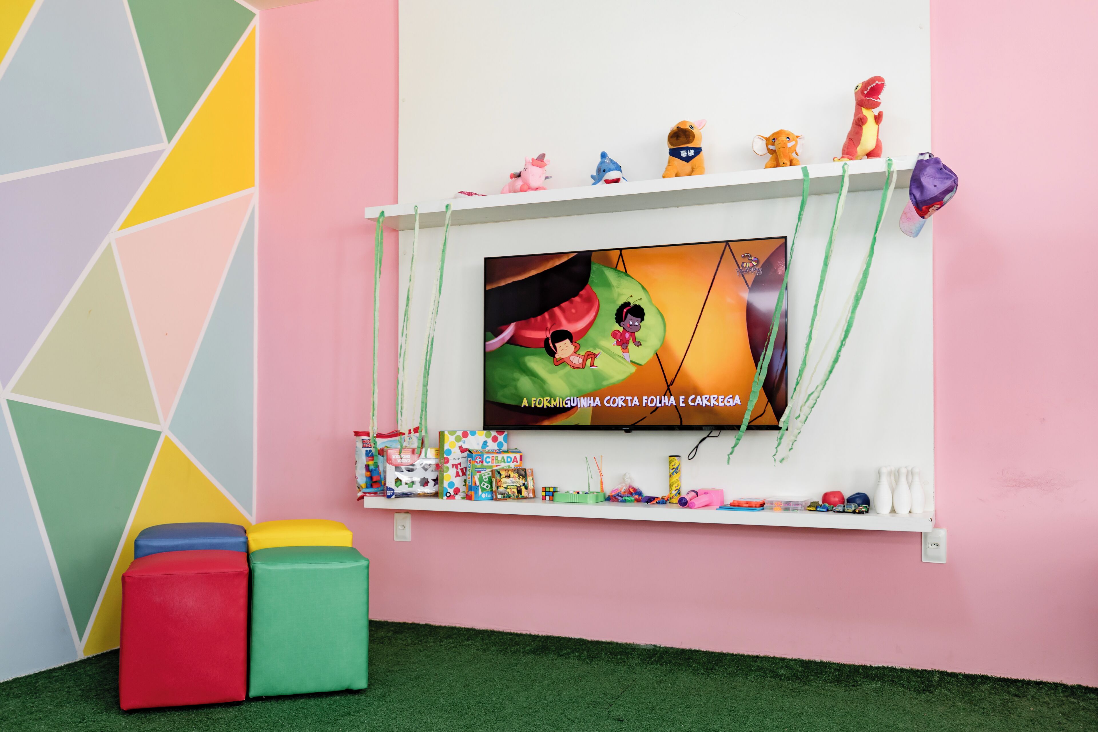 Un espace de jeux coloré équipé d’un téléviseur, de jouets et de bacs de rangement.