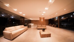 Una sala de estar moderna con un sofá color beige, una mesa de centro y una zona de estar con sillones y una mesita.