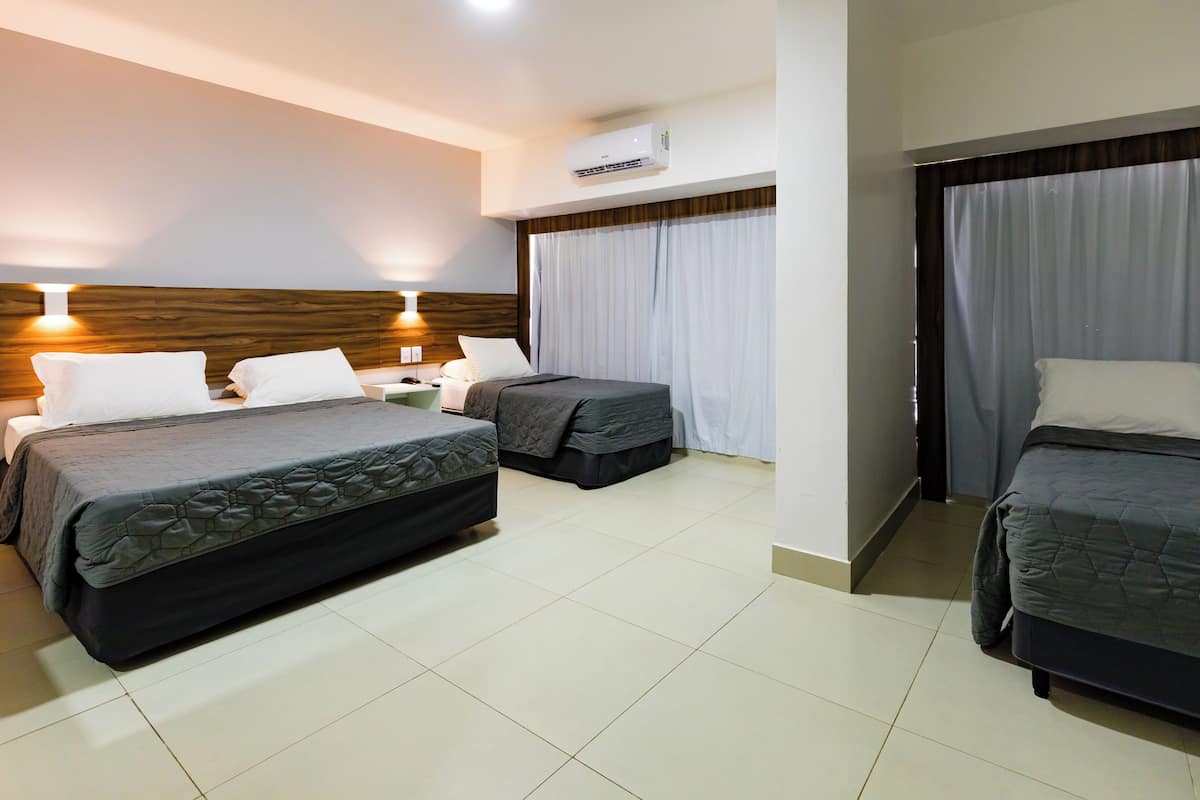 Habitación de hotel con dos camas, una mesita de noche, una lámpara y un equipo de aire acondicionado.