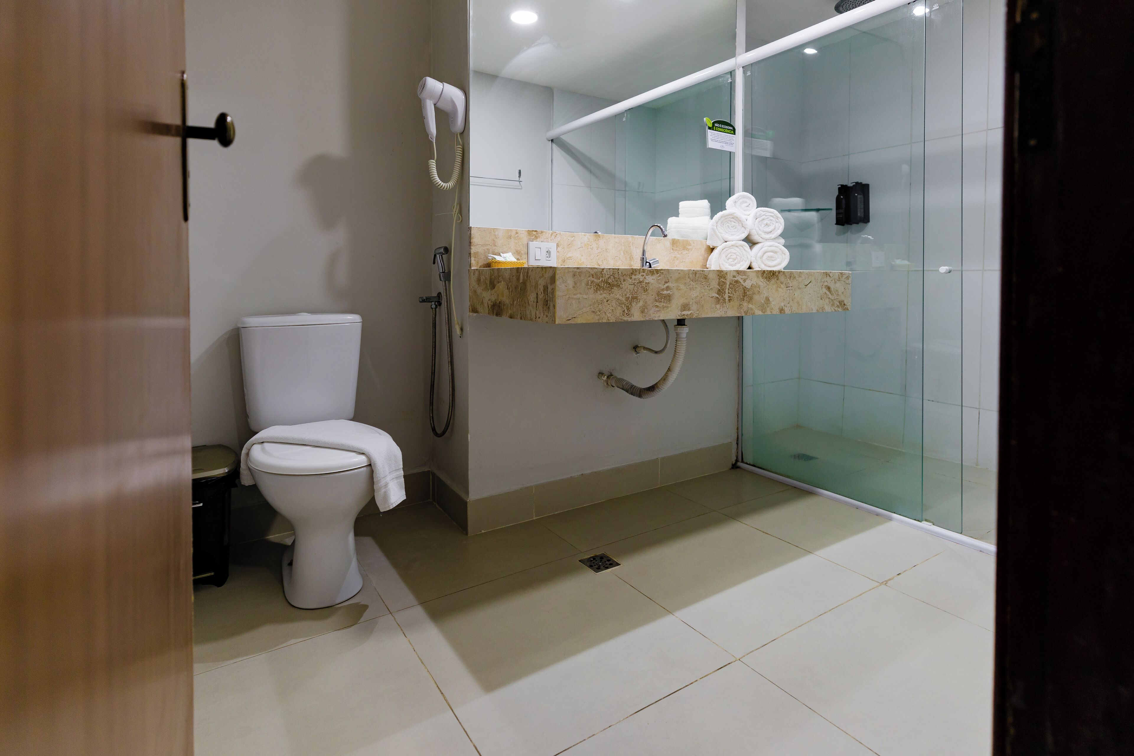 Un bagno moderno con un water, un box doccia in vetro e un mobile lavabo con asciugamani.