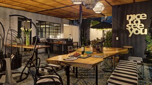 A dining area with a wooden table, black and white striped benches, and a wall with a sign that reads "nice to see you". - Casa Decu (Mexico City)