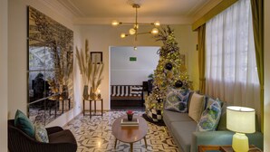A modern living room with a sofa, armchair, and coffee table, a Christmas tree, and a large abstract art piece on the wall. - Casa Decu (Mexico City)