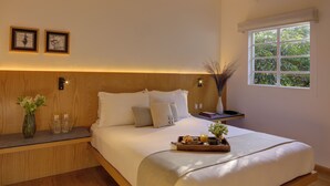 A neatly made bed with a tray of breakfast items, a vase of flowers, and a window with a view of greenery. - Casa Decu (Mexico City)