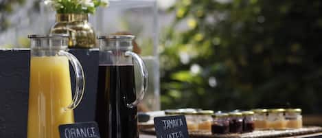 A beverage station with labeled drinks and jars of preserves.