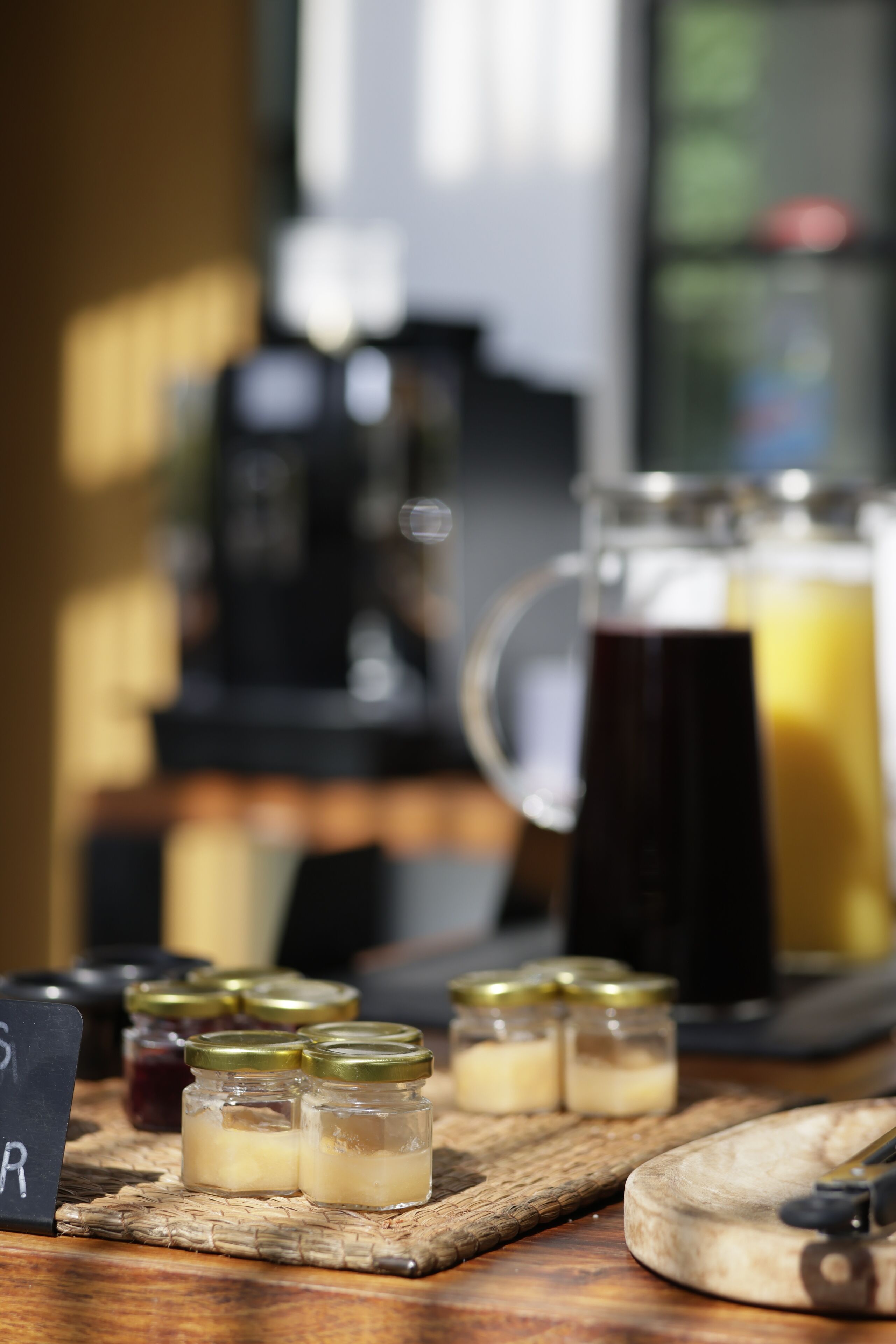 Une table avec des pots de condiments, un pichet de thé glacé et une machine à café.