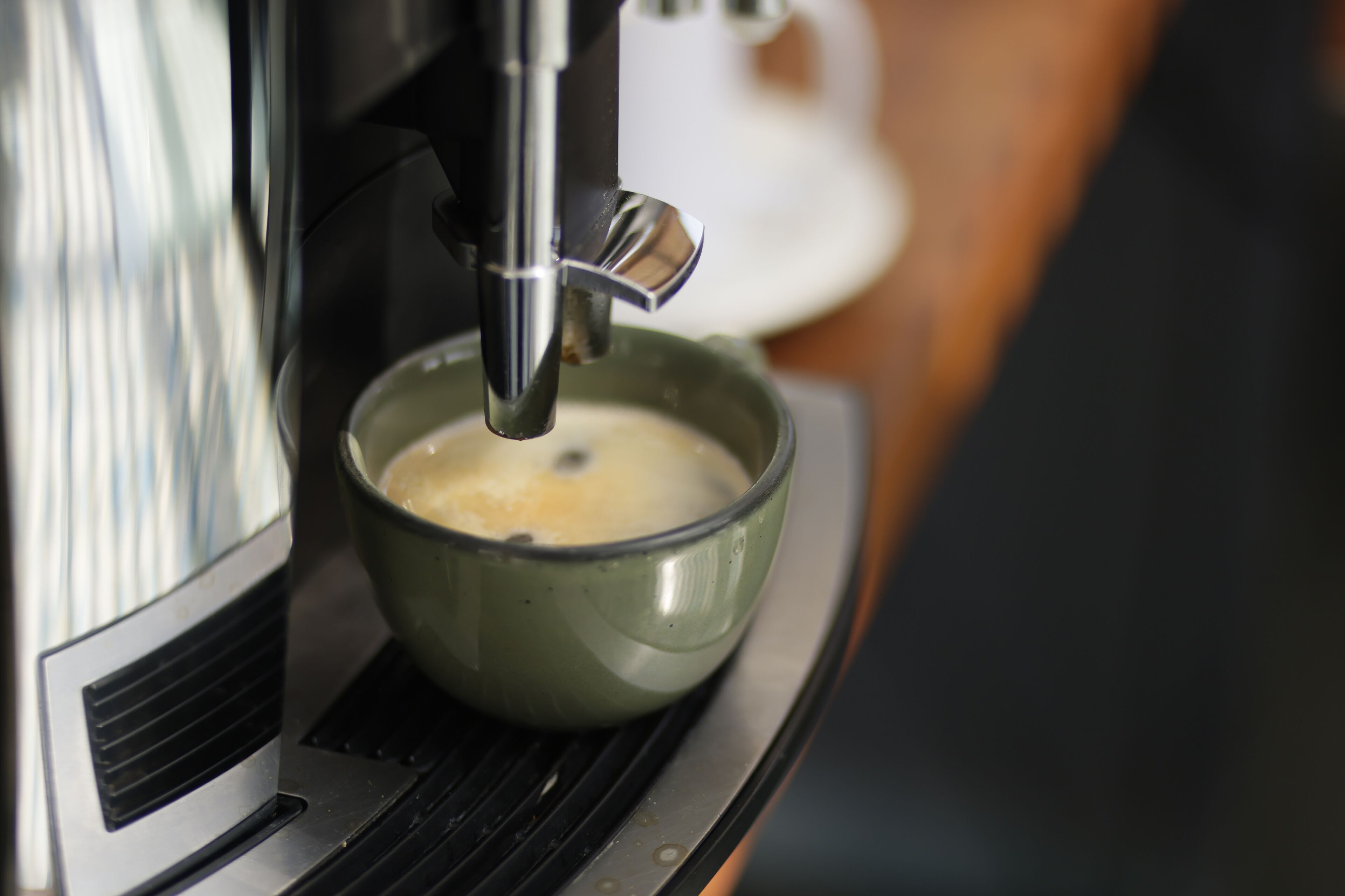 Une machine à café verse du café dans une tasse en céramique.