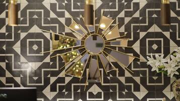 Um espelho decorativo com design em formato de sol numa parede estampada em preto e branco.