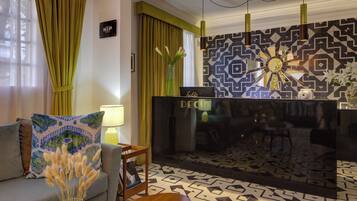Un moderno vestíbulo de hotel con un sofá, una mesa de centro, un jarrón decorativo, una chimenea y baldosas estampadas en el suelo.