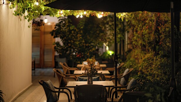 An outdoor seating area with tables and chairs, surrounded by plants and a warm, dimly lit ambiance. - Casa Decu (Mexico City)