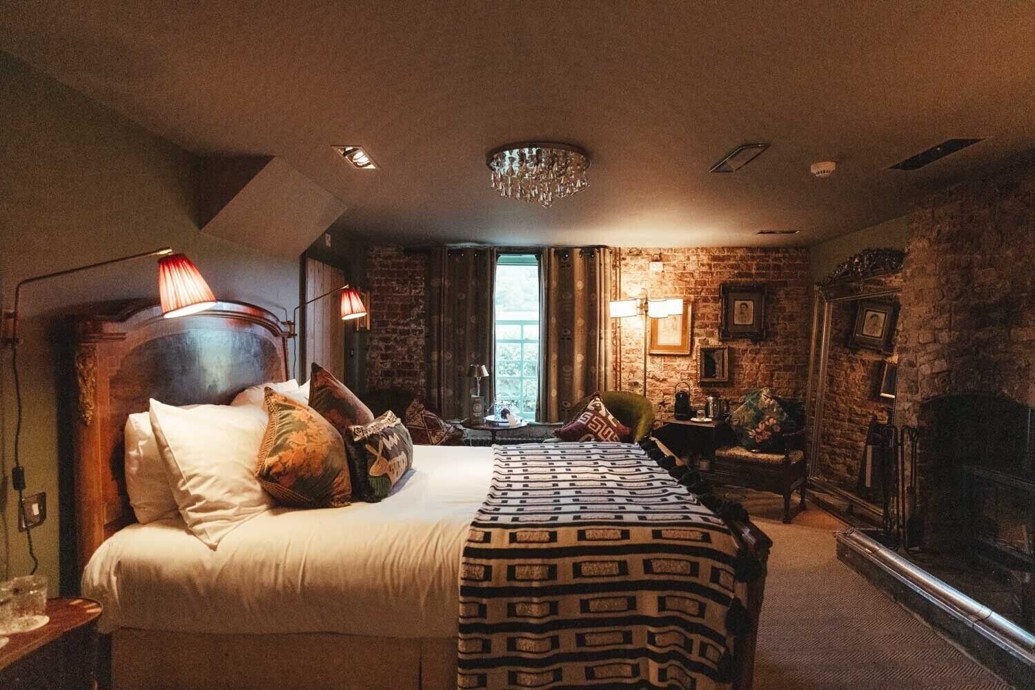A bedroom with a large bed, a fireplace, and a view of the outdoors.