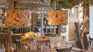 A restaurant interior with wooden tables, chairs, and hanging wine glasses. - The Five Bells Inn Brabourne (Ashford)