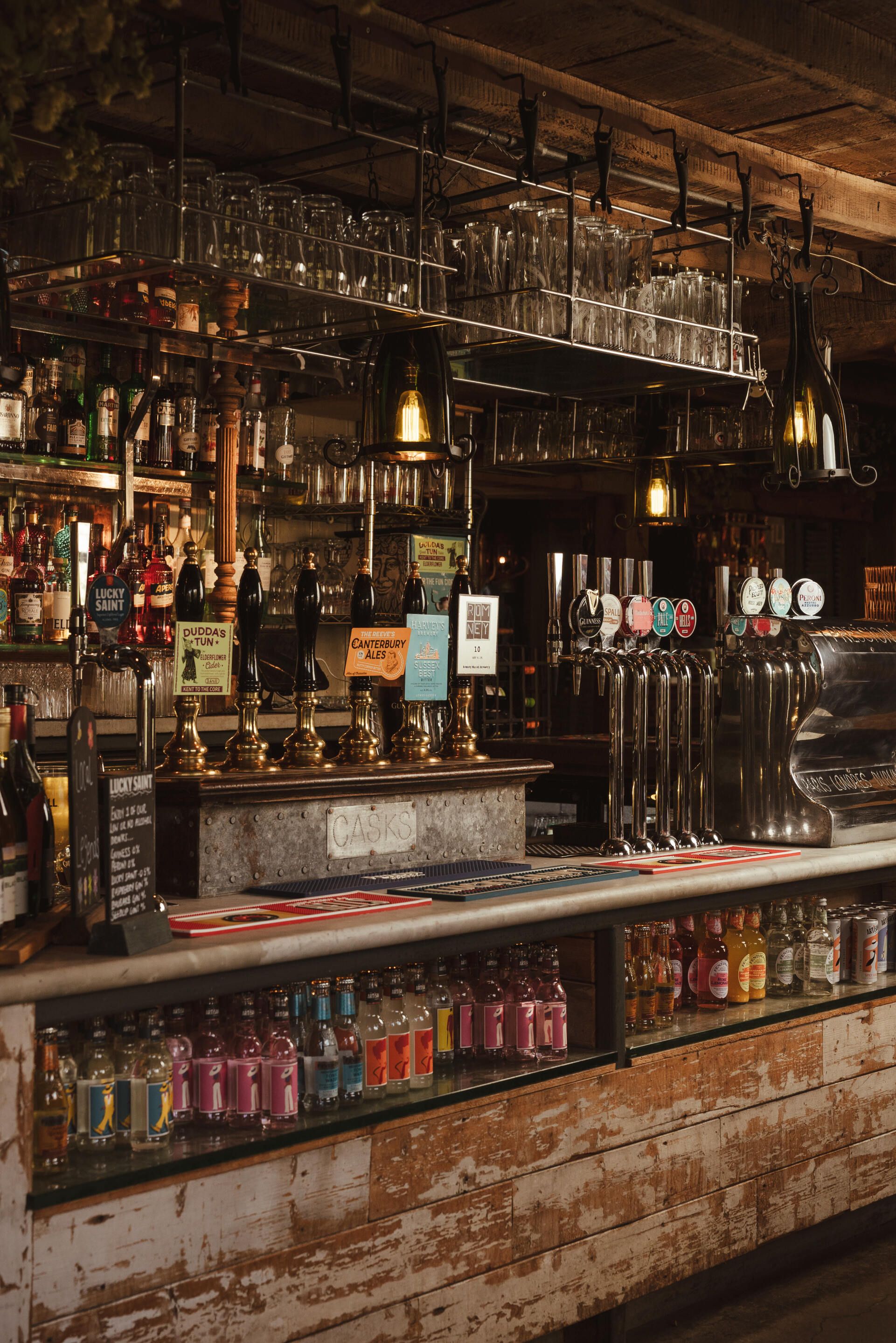 Un bar con varias cañas y estanterías llenas de botellas.