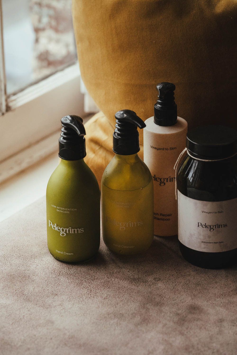 Four skincare bottles of varying sizes and shapes on a textured surface.