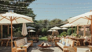 An outdoor patio area with wooden furniture, including sofas and tables, under white umbrellas. - The Five Bells Inn Brabourne (Ashford)