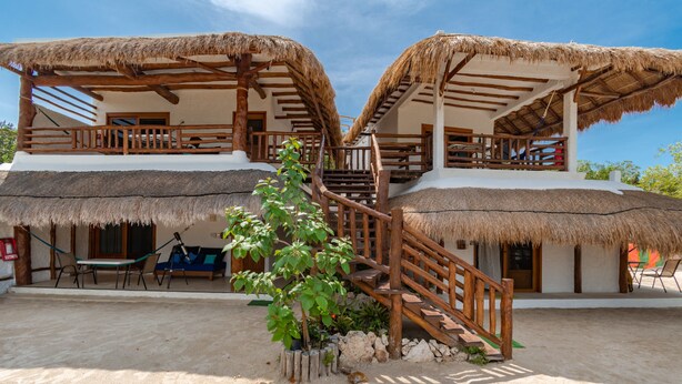 A two-story building with thatched roofs and wooden balconies. - La Casa del Alux - Adults Only (Isla Holbox)