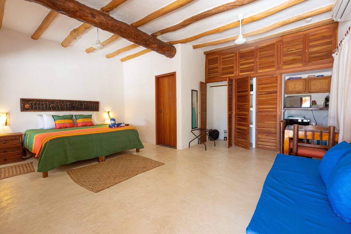 Un dormitorio con cama, sofá, armarios de madera y escritorio.