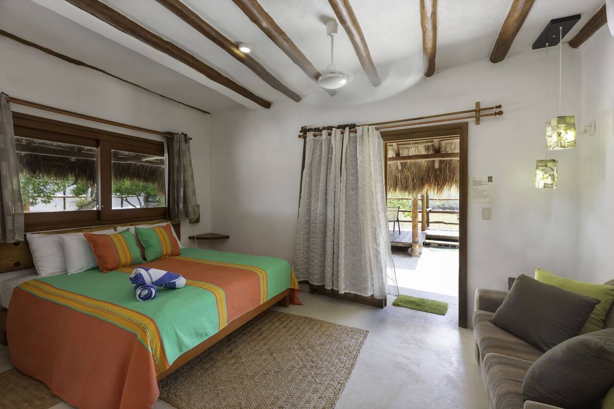 Un dormitorio con cama, sofá, ventana y puerta que da a un espacio exterior.