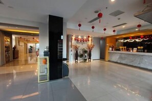 Eine Hotelhalle mit einer Rezeption, einer Treppe und einem Zierbogen.