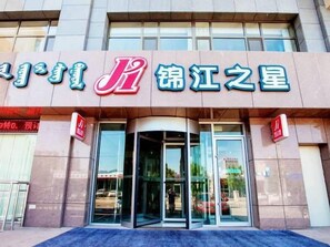 Un bâtiment avec une enseigne indiquant « Jiang Jiang Star » et une porte tournante à l’entrée.