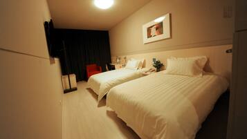 A hotel room with two beds, a desk, a chair, a nightstand, and a ceiling light.