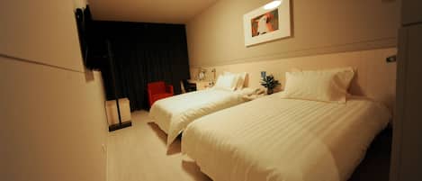 Habitación de hotel con dos camas, un escritorio, una silla, una mesita de noche y una lámpara del techo.