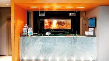A reception area with a marble counter, a large flat-screen TV, and a clock on the wall.
