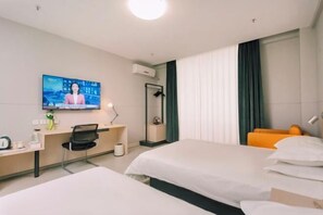 Habitación de hotel con dos camas, un escritorio con silla, televisor montado en la pared y una ventana con cortinas.