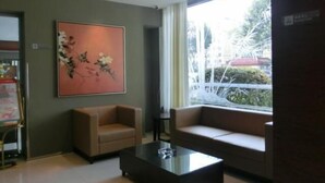 A modern room with a beige sofa, a glass coffee table, and a large window offering a view of greenery outside. - Jinjiang Inn (Xiangyang Ancient City Tanxi Road Branch) (Xiangyang)