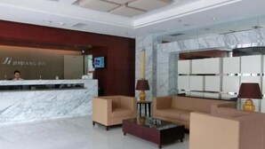 A hotel lobby with a reception desk, marble flooring, sofas, and a large mirror. - Jinjiang Inn (Xiangyang Ancient City Tanxi Road Branch) (Xiangyang)
